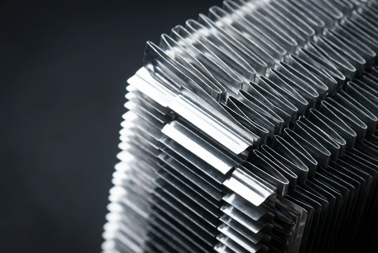 Gros plan macro sur les ailettes d'un condenseur de climatisation neuf pour Clio 3, sur fond neutre.